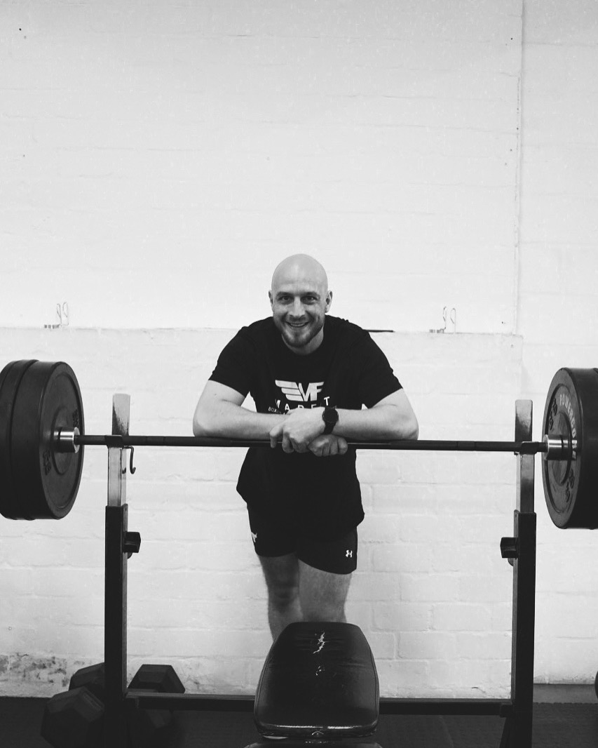 Coach leaning on a loaded bench press bar